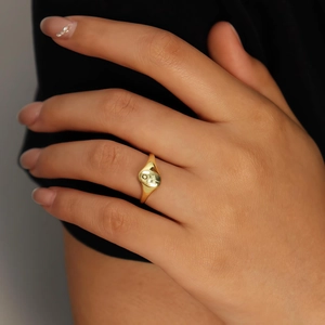 Close-up of gold signet ring with sun and cloud engravings on a woman's finger