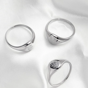 Three-piece set of silver signet rings with floral engravings on polished steel