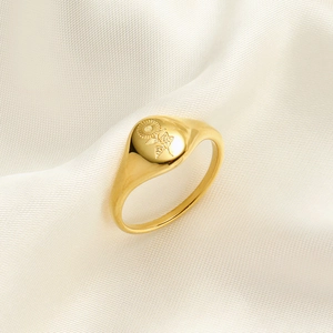 Detailed view of a gold-plated signet ring with intricate floral sunburst engraving