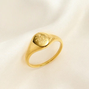 Detail of vintage gold oval signet ring with floral engraving on silk fabric