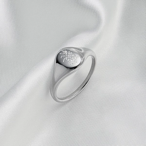 Detail of silver oval signet ring featuring delicate floral engravings on silk background
