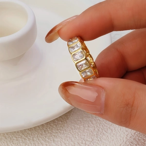 Macro detail of a gold eternity ring with rectangular zircons on polished metal