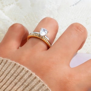 Close-up of pear-cut solitaire diamond ring paired with a pavé gold band on hand