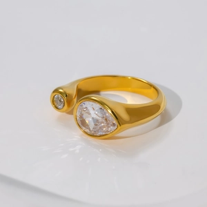 Detailed close-up of golden teardrop and round zircon stones on a polished open ring