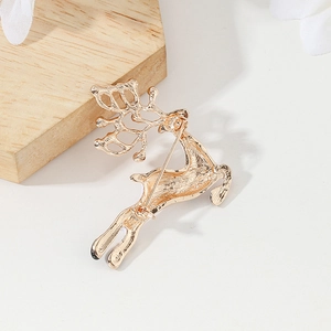 Golden reindeer Christmas brooch back detail with secure pin on light wood display