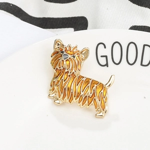 Vibrant enamel Yorkshire Terrier brooch in gold finish resting on a ceramic dish