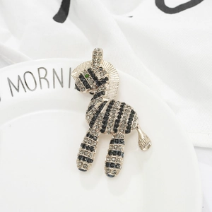 Zebra brooch in gold metal with black and grey rhinestones on a white plate