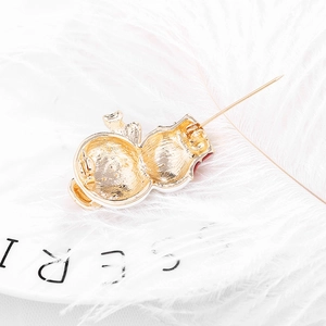 Golden snowman Christmas brooch with long pin on a white ceramic plate with a feather