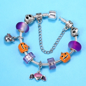 Bracelet serpent d'Halloween avec citrouille, crâne et perles violettes sur fond bleu