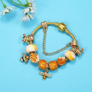 Golden charm bracelet with bee and maneki-neko beads on a light blue background