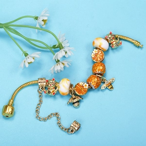 Golden snake chain bracelet with Maneki Neko cat and honey bee charms on blue background
