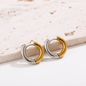 Detailed view of two-tone gold and silver mixed metal hoop earrings on stone