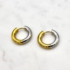 Detail of two-tone 18K gold and silver stainless steel hoop earrings on marble