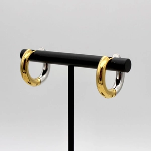 Classic two-tone 18K gold and silver stainless steel hoop earrings on a display