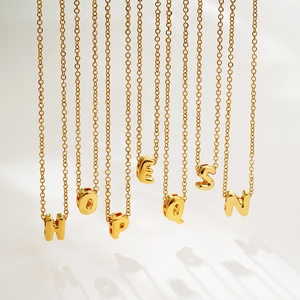 Close-up of golden bubble letter pendants with polished mirror finish on fine chains
