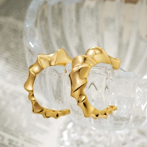 Macro shot of thick gold twisted hoop earrings hanging on embossed glass with vintage background