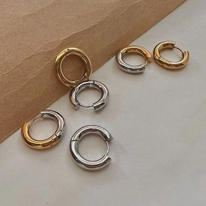 Macro detail of classic 18K gold and silver two-tone thick huggie hoop earrings