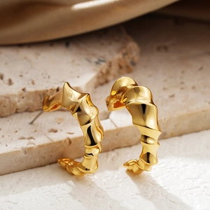Exaggerated C-shaped twisted gold earrings with a sculptural bamboo-style thread design