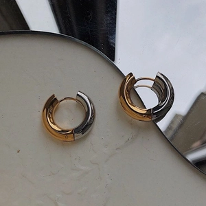 Close-up of two-tone gold and silver chunky hoop earrings with polished mirror finish