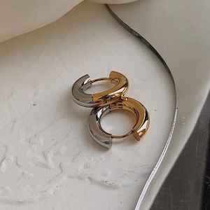 Macro view of bicolor gold and silver chunky hoop earrings on a stone tray