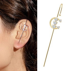 Detail of gold piercing ear cuff with white zircon stones on model's ear cartilage