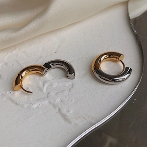 Macro detail of two-tone 18K gold and silver stainless steel hinged hoop earrings