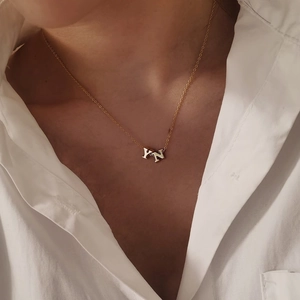 Close-up of golden bubble initial pendants Y and N on a dainty stainless steel chain