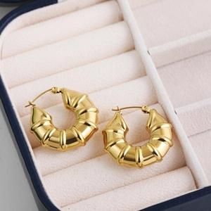 Golden chunky twisted hoop earrings with croissant rib texture in a blue velvet jewelry box