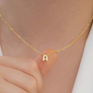 Close-up of golden 3D bubble letter A pendant on a delicate stainless steel cable chain