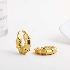 Detailed view of chunky 18K gold plated bamboo style hoop earrings on white background