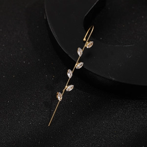 Close-up of golden lightning bolt earring with marquise zircon stones on black background