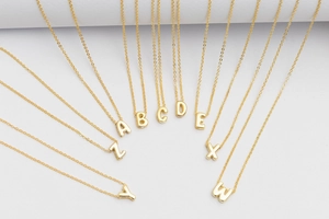 Detailed close-up of golden bubble initial pendants with high-polish mirror finish