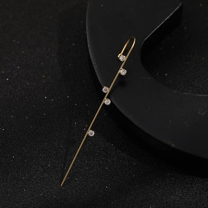 Macro view of gold plated ear crawler with five inlaid zircons on a dark background