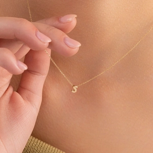 Close-up of polished gold S letter pendant on a delicate cable chain necklace