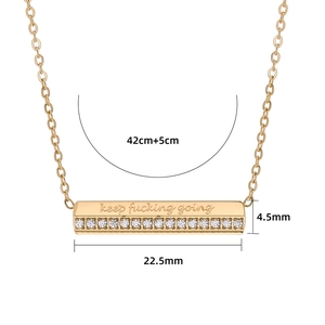 Dettaglio della collana a barra dorata con pavé di zirconi e incisione keep fucking going