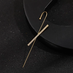 Macro detail of gold lightning bolt ear cuff with micro-pave zircons on black background