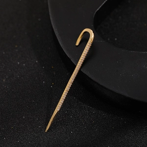 Macro shot of gold lightning stud earring with pavé zircons on black background