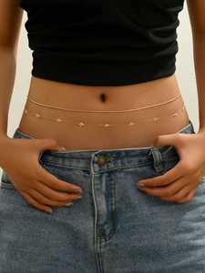 Detail of a double-layered gold waist chain with shimmering triangle sequins on the skin