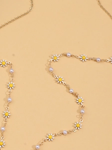 Close-up of golden daisy body chain with white enamel petals and round pearls