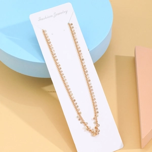 Detail of gold layered body chain with star charms and textured discs on jewelry card