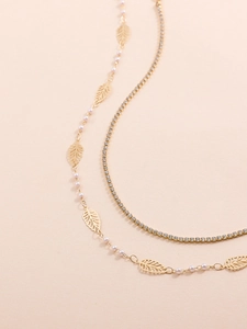 Close-up of golden leaf charms and sparkling rhinestone tennis chain with white pearls