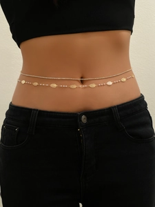 Detail of a double-layered gold waist chain with rhinestones, metal leaves and white pearls