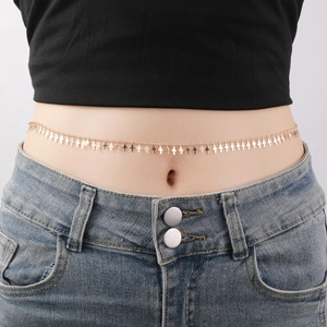 Close-up of gold waist chain featuring small cross charms worn over denim jeans