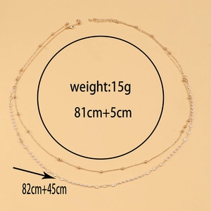Detail of double-layer gold body chain with white beads and transparent round charms