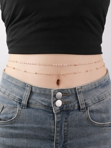 Close-up of double-layer gold belly chain with pearls and beads on model's waist