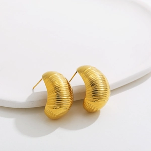 Close-up of golden stainless steel stud earrings with distinctive ribbed texture design