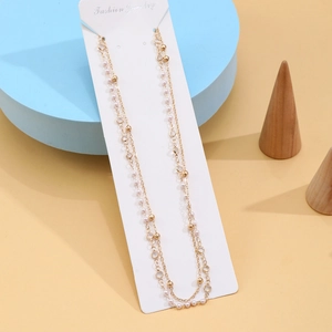 Detail view of double-layer gold body chain with crystal beads and white faux pearls
