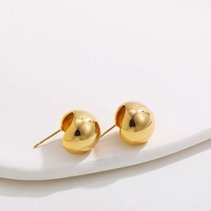 Close-up of 18K gold-plated hemisphere stud earrings on a minimalist white stone pedestal