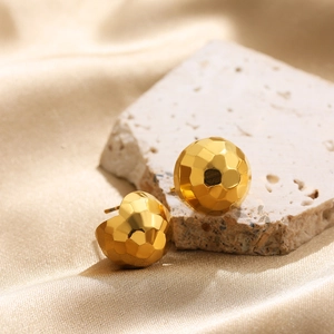 Macro shot of gold sphere stud earrings with geometric hammered texture on stone base