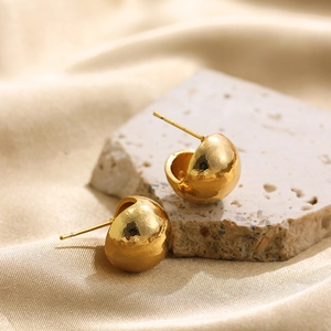 Detailed close-up of 18K gold-plated earrings with hammered texture on a silk background